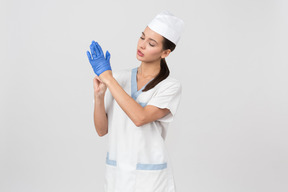 Attraktive krankenschwester in einem medizinischen gewand, das wegwerfhandschuhe auszieht