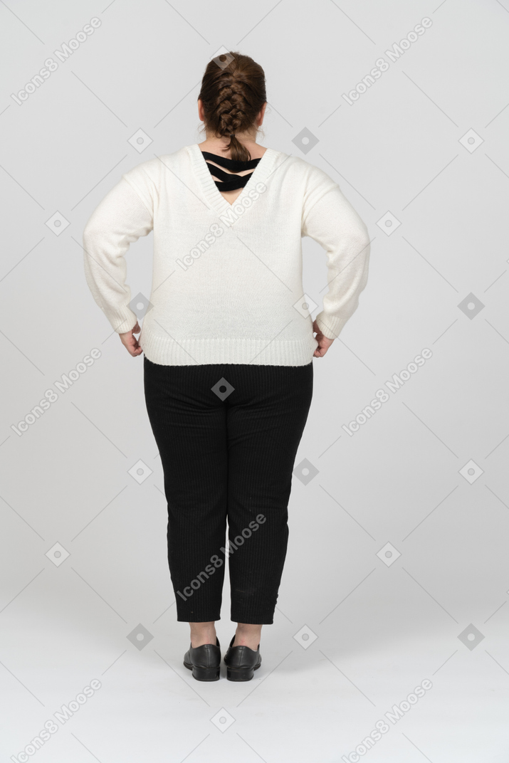 Rear view of a plump woman in white sweater posing