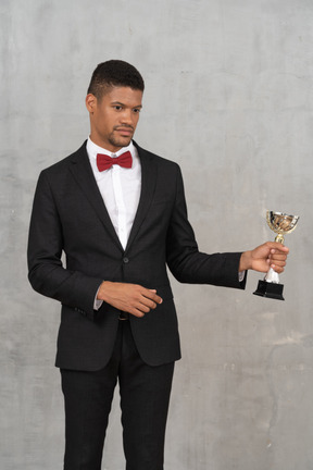 A man in a tuxedo holding a trophy