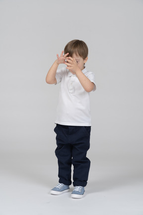 Front view of a little boy covering his face