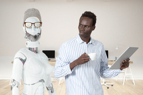 A man standing next to a robot holding a tablet