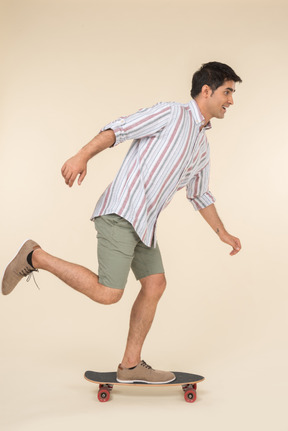 Young caucasian guy standing on skate in profile