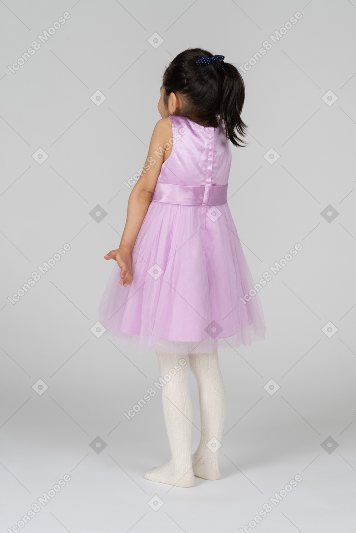 Little girl in a pretty dress shrugging her shoulders