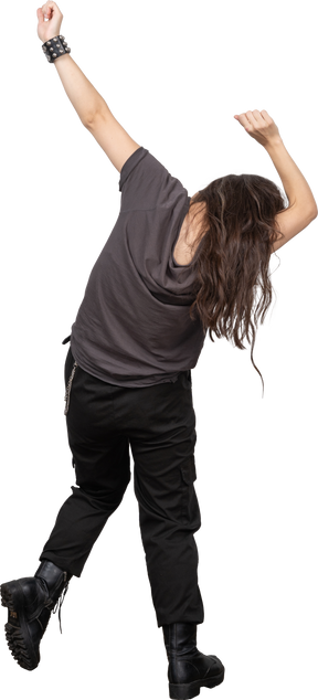 彼女の手を上げながら踊っている若い女性の背面図
