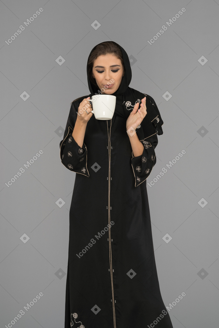 Young muslim woman blowing on a cup