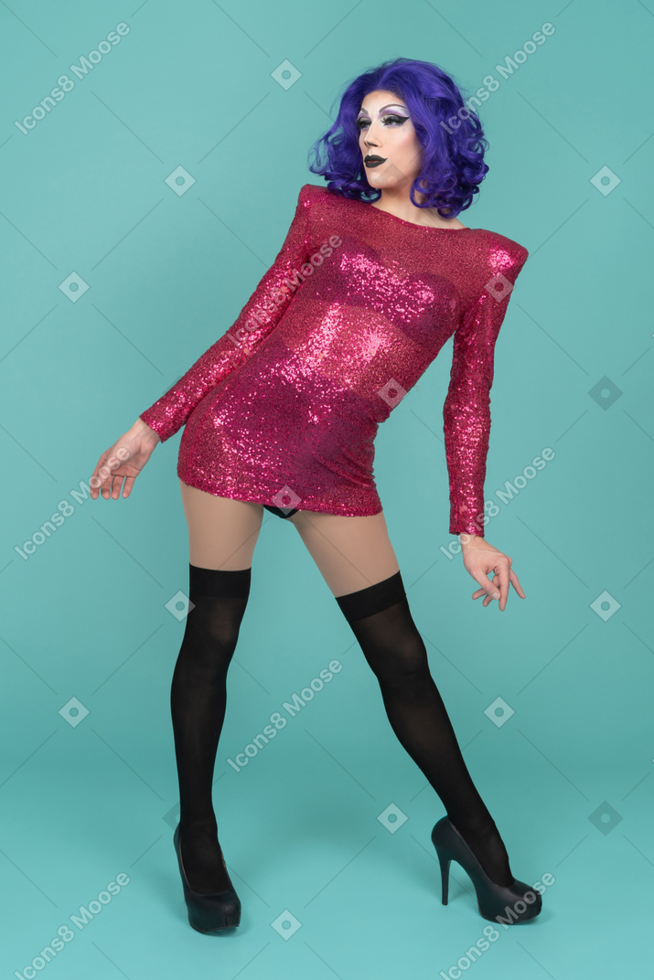 Portrait en pied d'une drag queen en robe rose penchée sur le côté