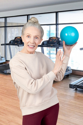 A woman holding a blue ball in a gym