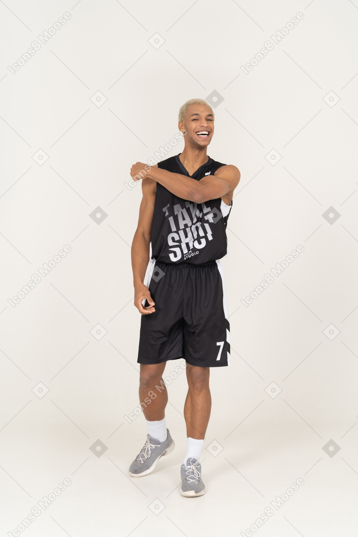 어깨를 만지고 웃는 젊은 남성 농구 선수의 전면보기