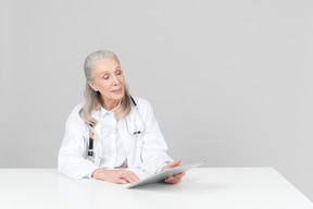 Aged female doctor working on a digital tablet