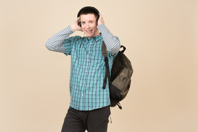 Студент стоит с рюкзаком и наушниками