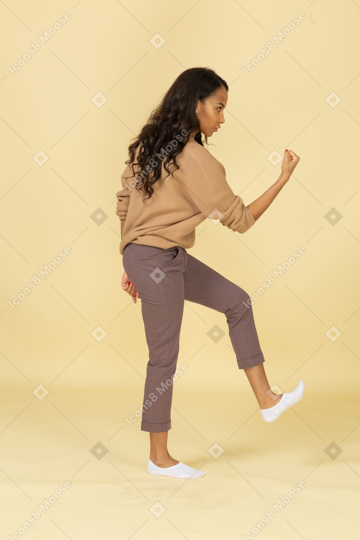Side view of an angry dark-skinned young female raising hand