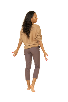 Back view of a dark-skinned young female outspreading hands