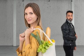 Woman with grocery bag and man looking at her