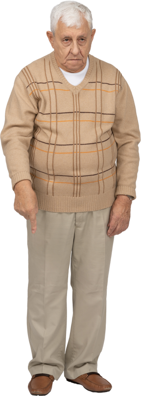 Vista frontal de un anciano con ropa informal apuntando hacia abajo con el dedo