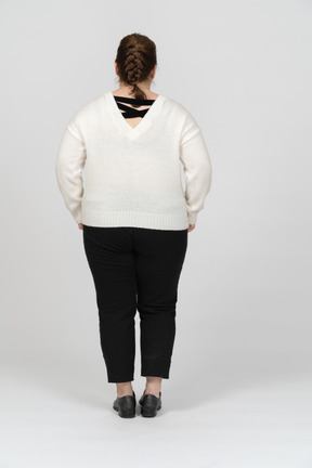 Rear view of a plump woman in white sweater posing