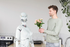 A man standing next to a robot holding a bouquet of flowers