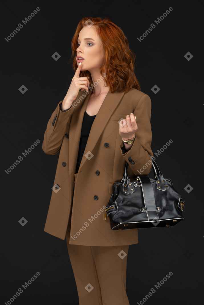 Mujer joven en un traje marrón tocando su labio