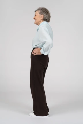 Side view of an old woman smiling with a hand on a hip