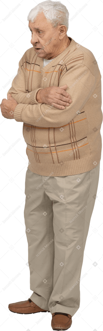 Vista frontal de un anciano asustado con ropa informal abrazándose a sí mismo