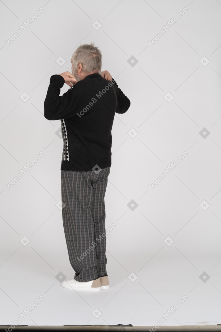Пожилой мужчина стоит, положив руки на плечи