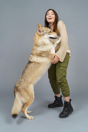 In voller länge einer glücklichen meisterin, die mit ihrem hund spielt