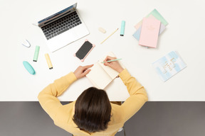 Eine büroangestellte macht sich notizen am tisch