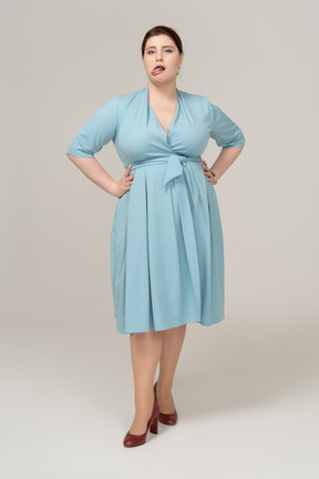 一个穿着蓝色裙子的女人的前视图，双手叉腰，露出舌头