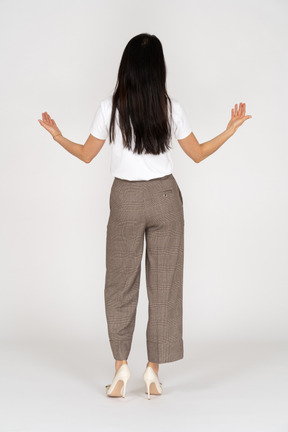 Vista posteriore di una giovane donna in calzoni protese le mani