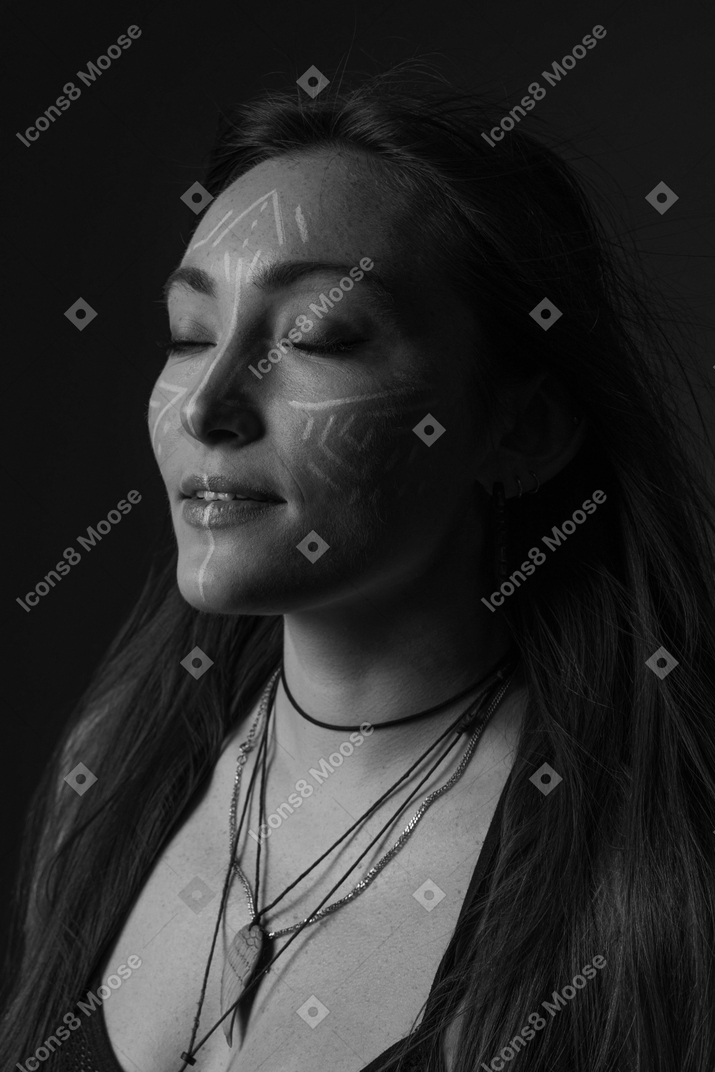 Side view noir picture of a young female with face art and her eyes closed