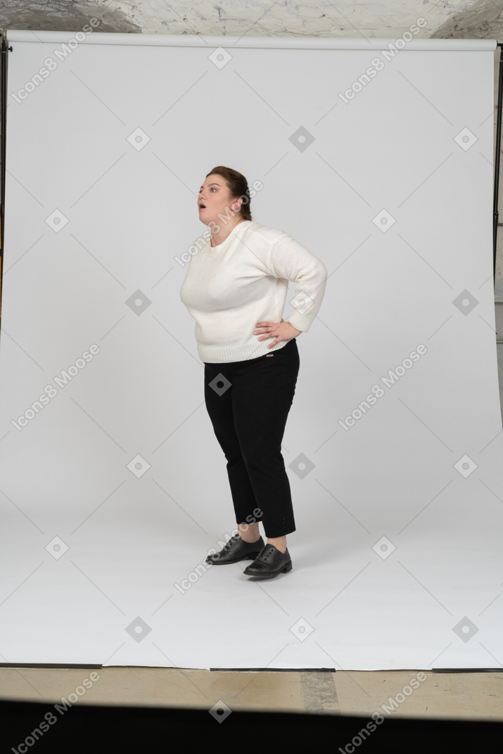 Вид сбоку на женщину больших размеров в повседневной одежде, стоящую с руками на бедрах