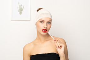 Portrait of a young woman sticking syringe into her mouth