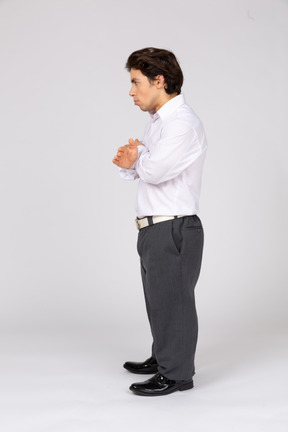Side view of a serious man standing with his hands crossed