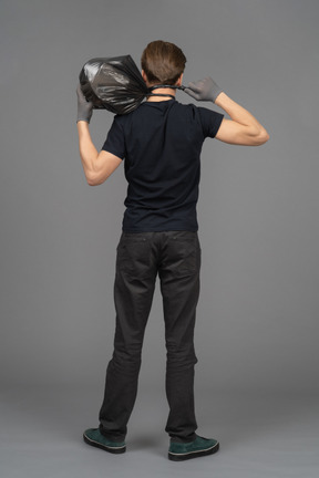 Un joven sosteniendo una bolsa de basura detrás de su cabeza