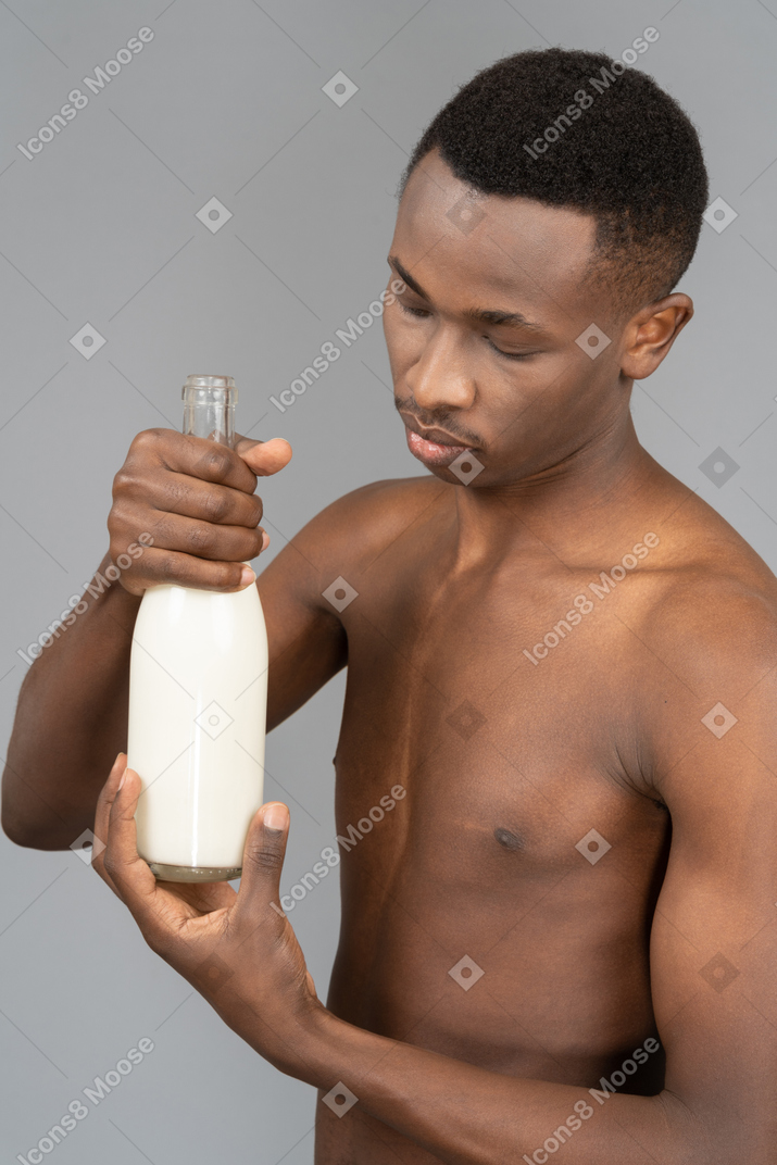 Junger mann mit einer flasche milch