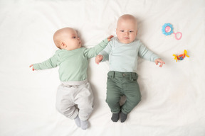 Bebés gemelos acostados boca arriba uno al lado del otro