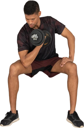 Young man in sports clothes lifting weigths