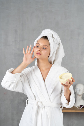 Mujer en bata de baño aplicando crema facial