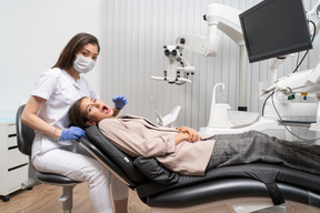 Full-length of a female dentist looking at camera while examining her female patient