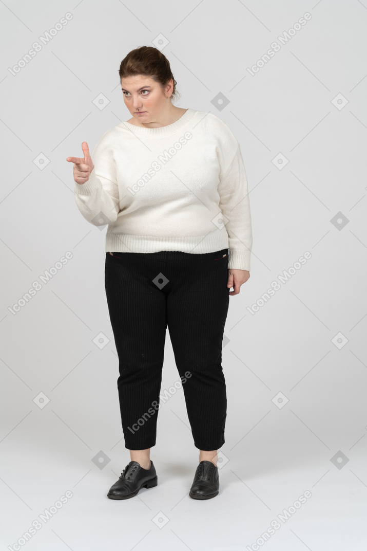 Front view of plump woman in casual clothes pointing with a finger