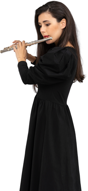 Vista laterale di una giovane donna seria in abito nero che suona il flauto