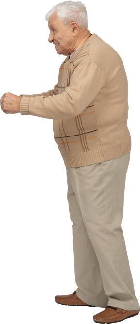 一个穿着休闲服、握紧拳头站着的快乐老人的侧视图