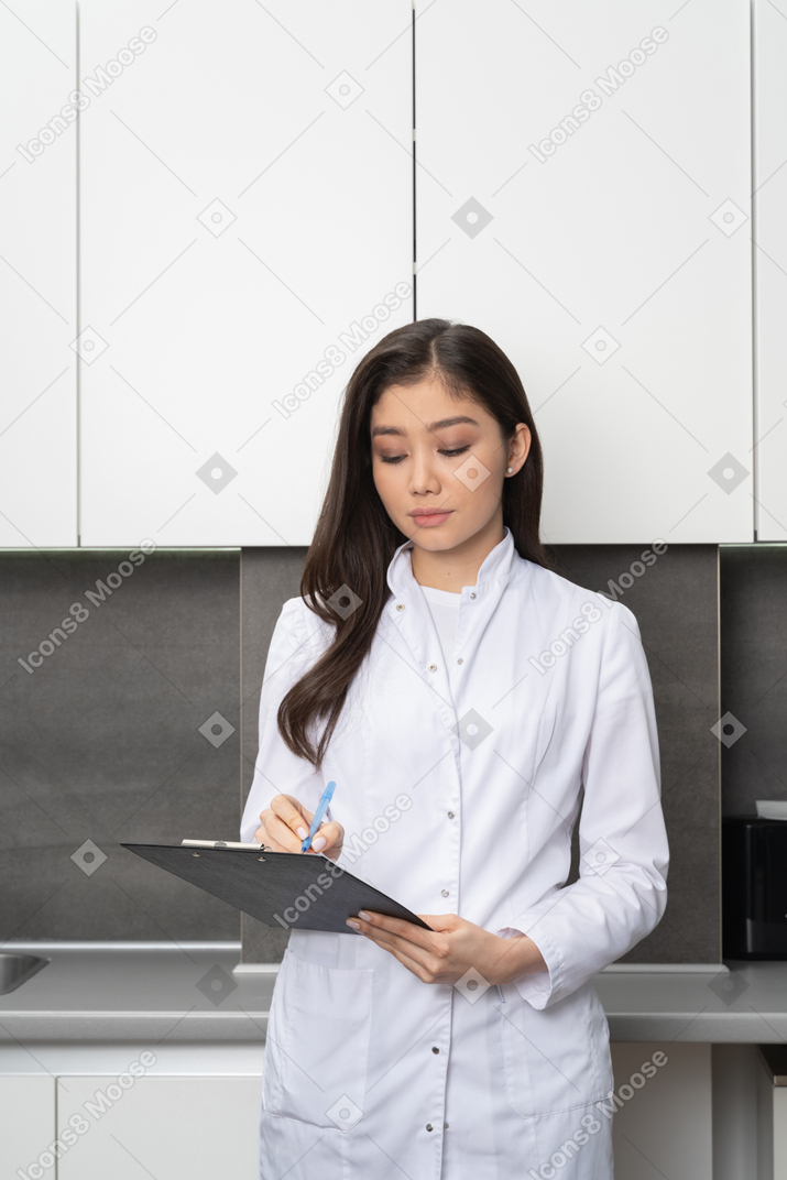 Vista frontal de una mujer joven mirando hacia abajo y tomando notas