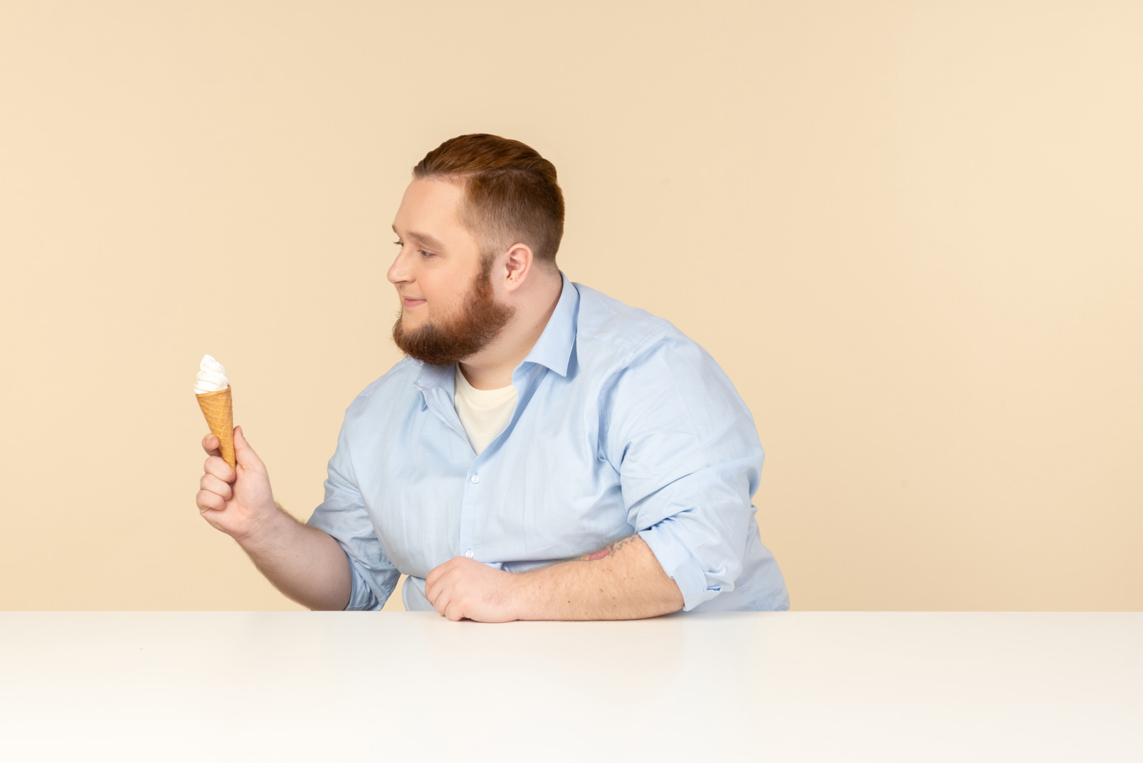 Big man sitting at the table and holding ice cream