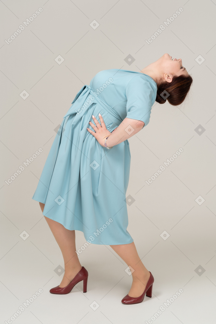 一个穿着蓝色连衣裙的女人向后倾斜的侧视图