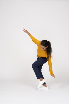 Side view of a girl in casual clothes posing with outstretched arms