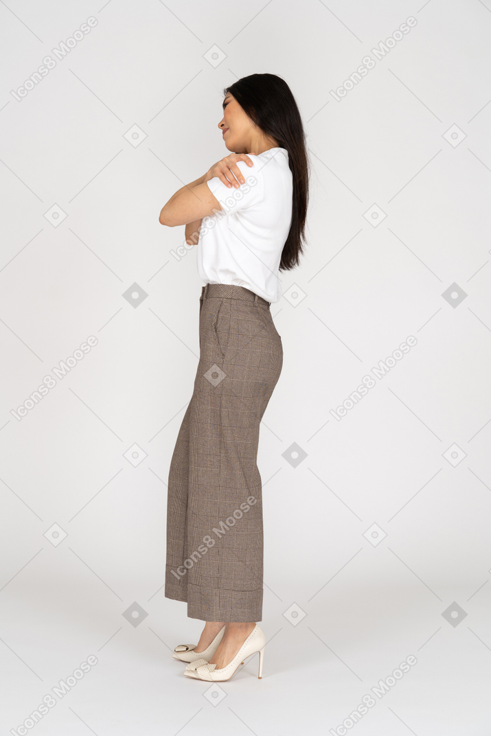 一位年轻的女士，穿着马裤和拥抱自己的t恤的侧视图