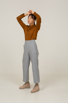 Three-quarter view of a young asian female in breeches and blouse raising hands