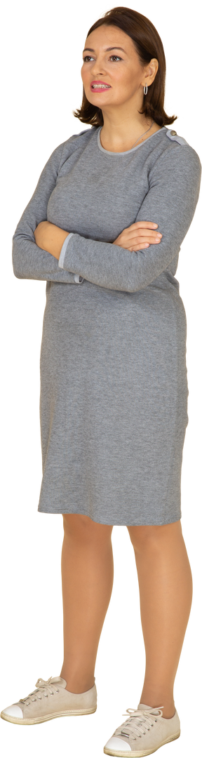 Vista frontale di una donna in abito grigio in piedi con le braccia incrociate