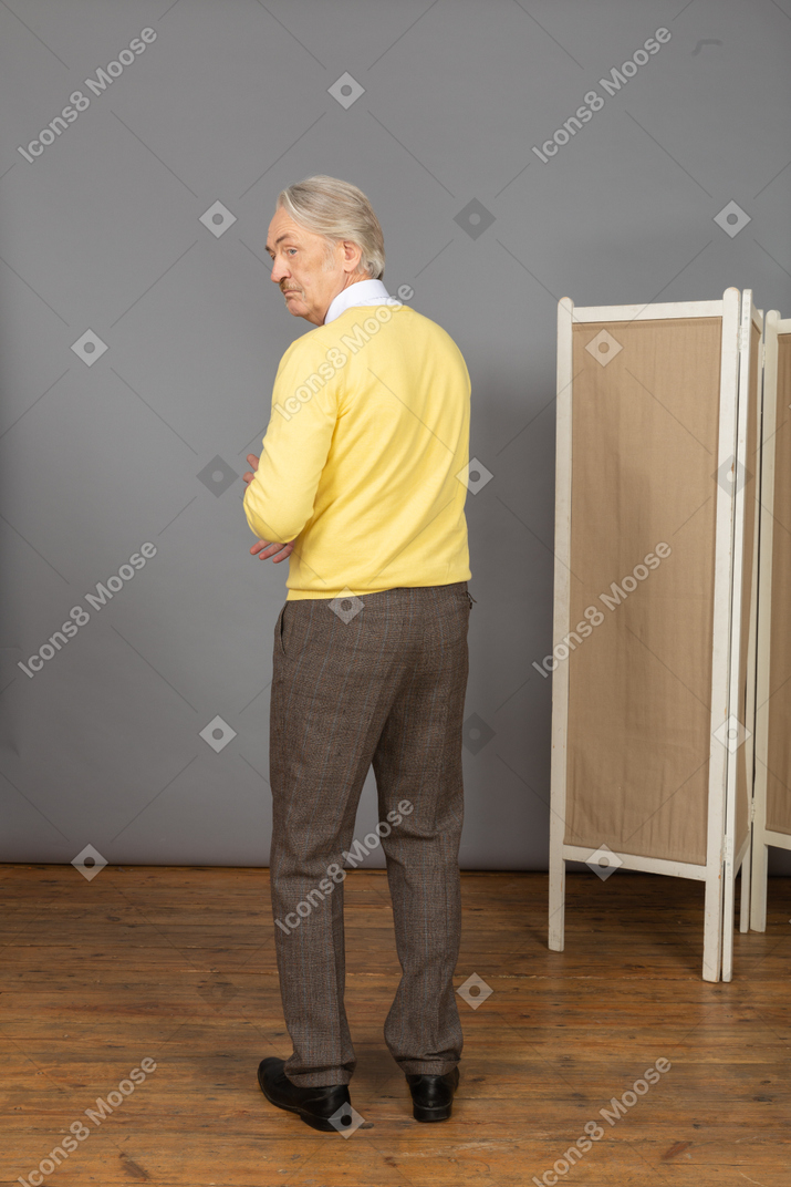 Back view of a gesticulating old man looking aside