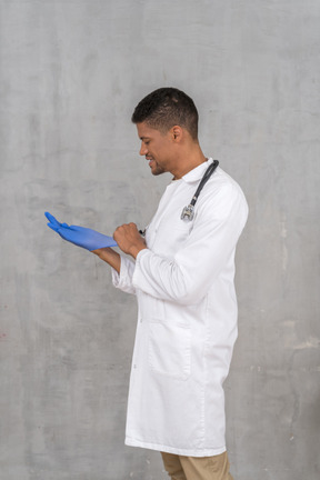 Male doctor putting on nitrile gloves